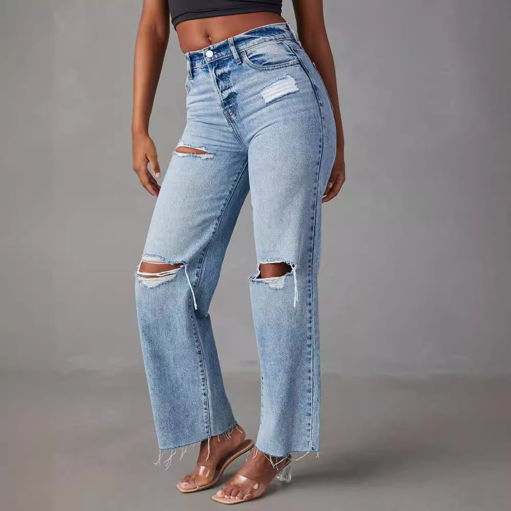 Person wearing ripped blue jeans on a gray background