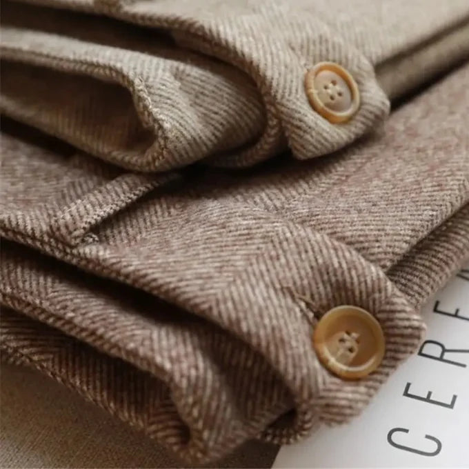 Close-up of folded brown fabric with buttons on a white surface
