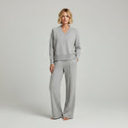 Person wearing a gray outfit standing in a room with a closet in the background.