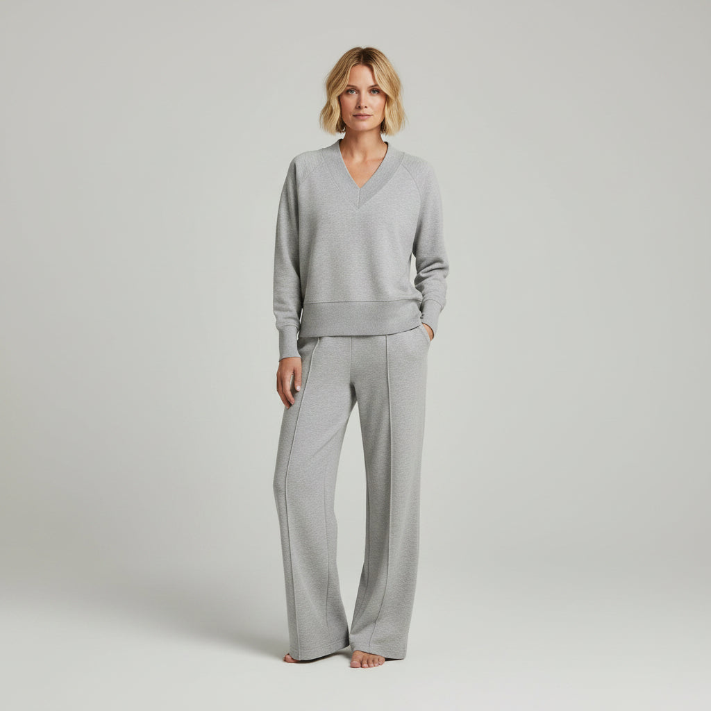 Person wearing a gray outfit standing in a room with a closet in the background.