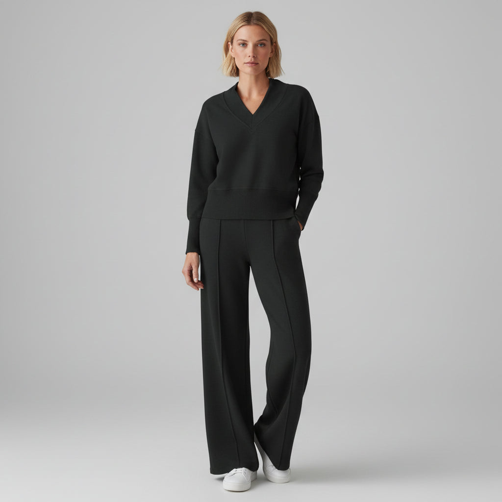 Person wearing a black outfit in a room with clothes in the background