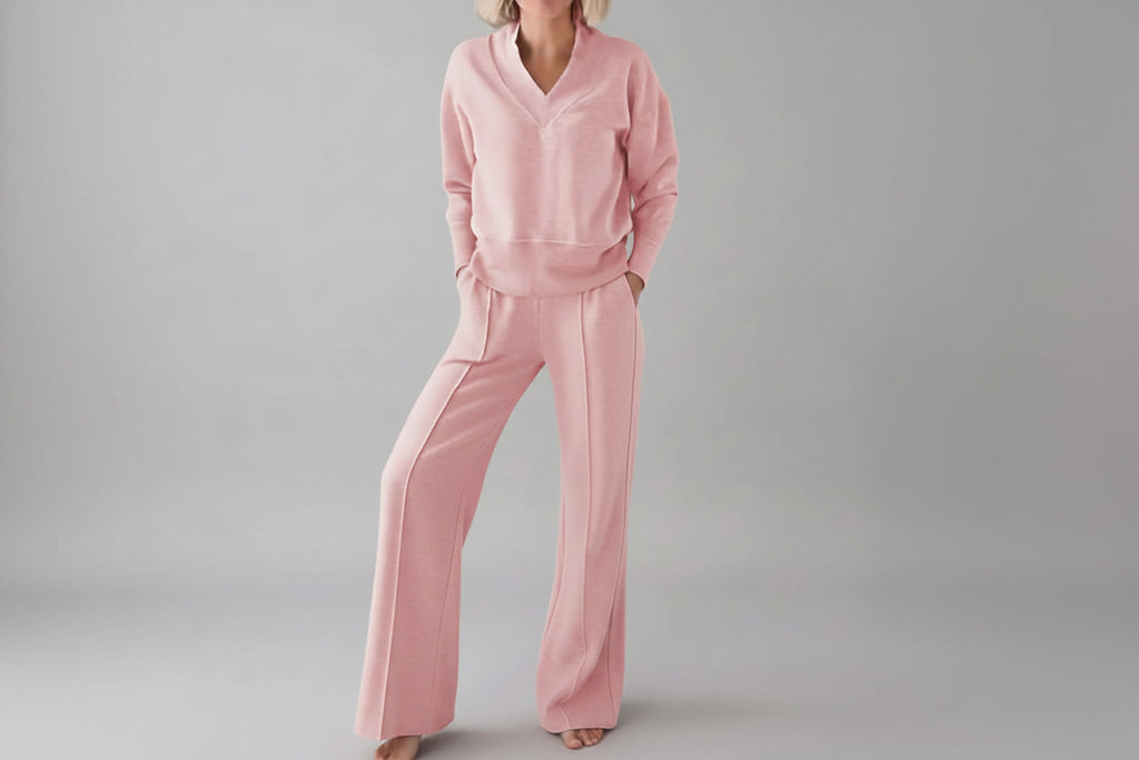 Person wearing a pink outfit in a room with clothes in the background
