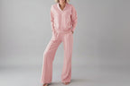 Person wearing a pink outfit in a room with clothes in the background