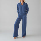 Person wearing a blue outfit in a room with clothes in the background