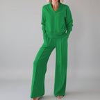 Person wearing a green outfit in a room with clothes in the background