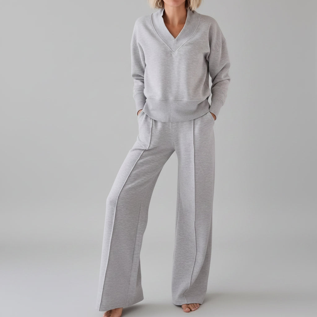 Person wearing a gray tracksuit in a room with clothes in the background
