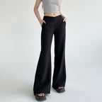 Person wearing black wide-leg pants and a gray crop top against a plain wall.