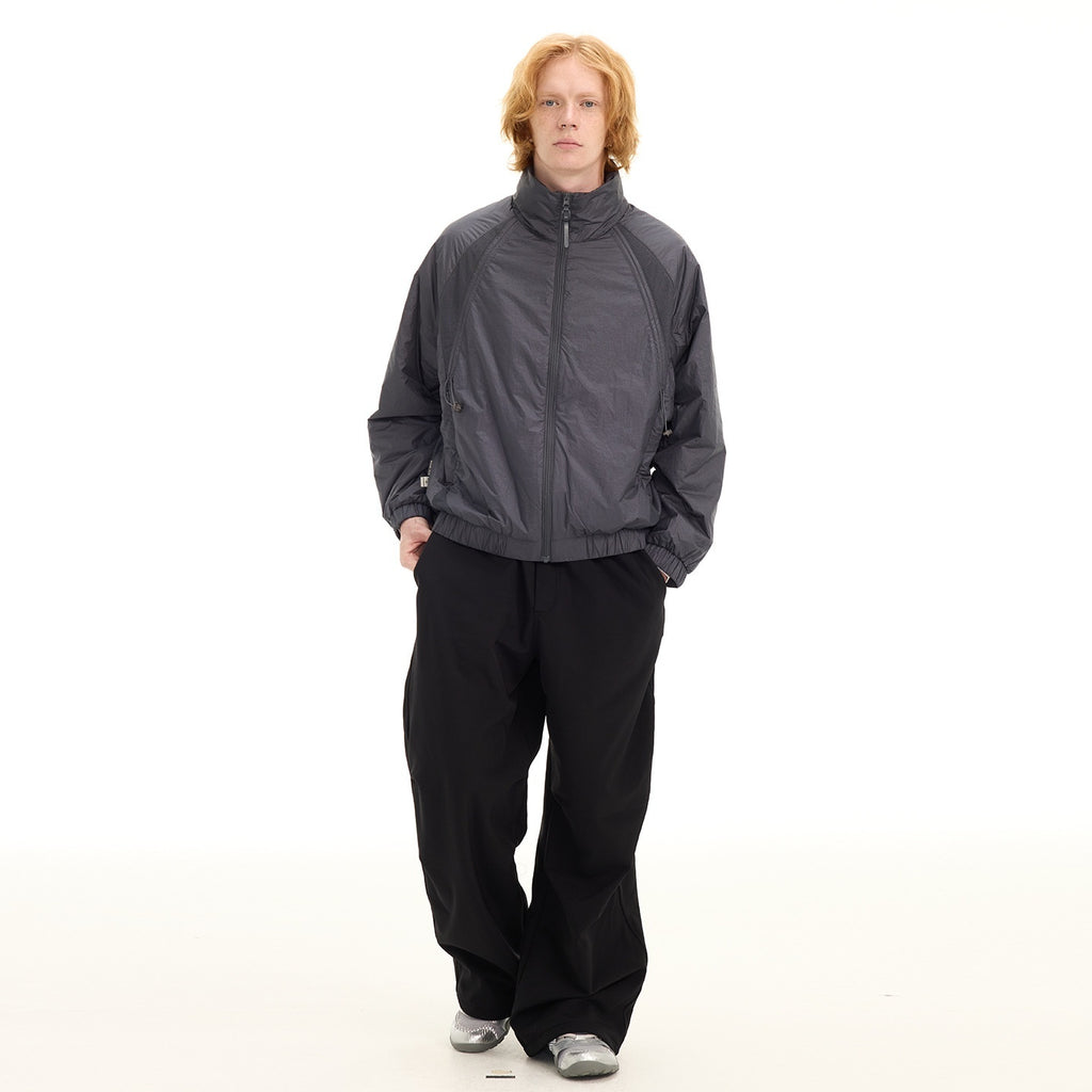Person wearing a gray jacket and black pants on a white background