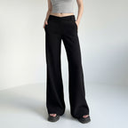 Person wearing black wide-leg pants and a gray top against a plain background