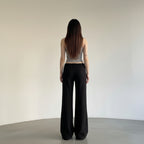 Person wearing black wide-leg pants and a gray top against a plain background