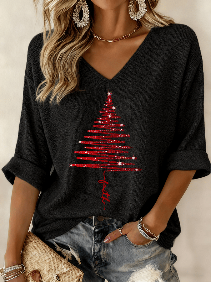 Black sweater with red Christmas tree design worn by a person, with a neutral background.