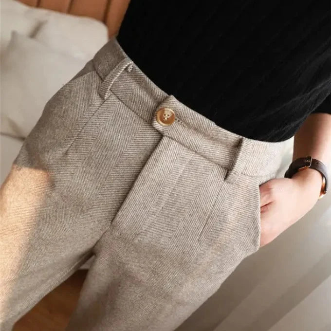 Close-up of a person wearing gray pants with a button, blurred background