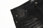 Close-up of black denim jeans with stitching details on a white background