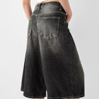 Black denim shorts worn by a person on a light gray background