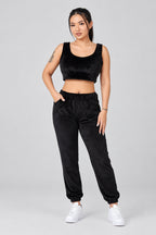 Woman wearing a black sleeveless top and black pants on a light gray background