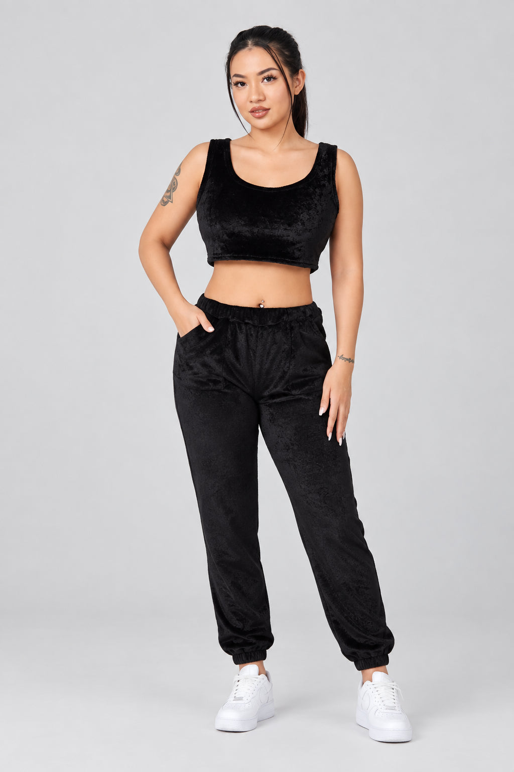 Woman wearing a black sleeveless top and black pants on a light gray background