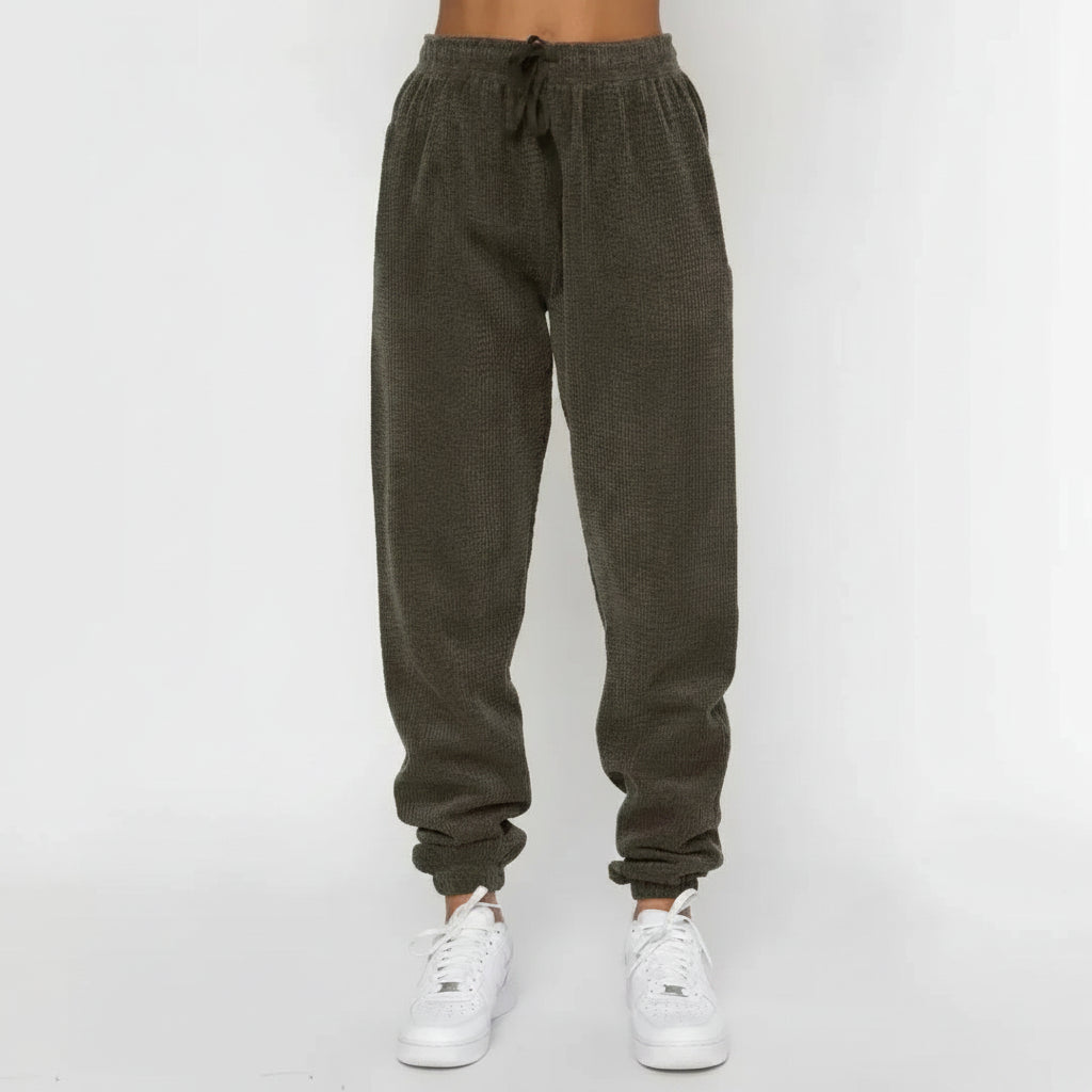 Dark gray sweatpants worn by a person on a white background