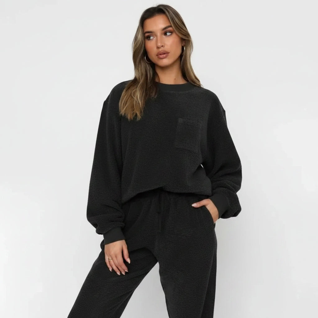 Woman wearing a black oversized sweater and pants set on a white background
