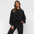 Woman wearing a black oversized sweater and pants set on a white background