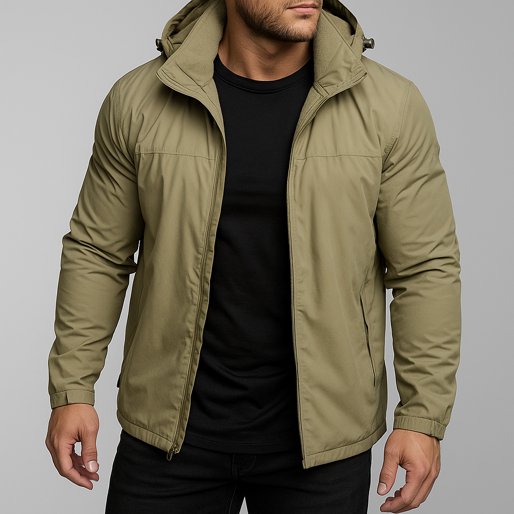 A man wearing an olive green hooded jacket over a black t-shirt, shown from the chin down against a solid gray background.