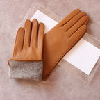 Pair of brown leather gloves with gray lining on a beige surface