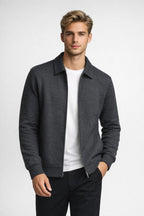 Man wearing a gray jacket over a white shirt on a light gray background