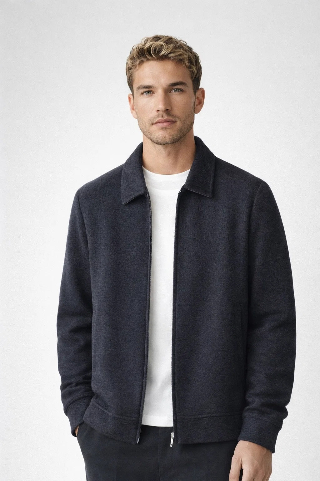 Man wearing a dark blue jacket over a white shirt on a light gray background