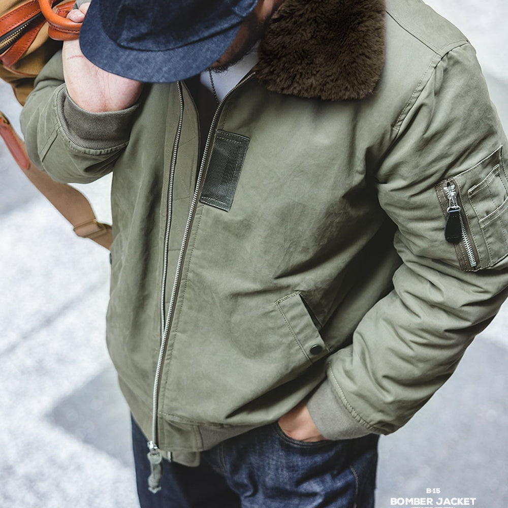 Person wearing a green bomber jacket with fur collar in a snowy setting