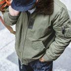 Person wearing a green bomber jacket with fur collar in a snowy setting