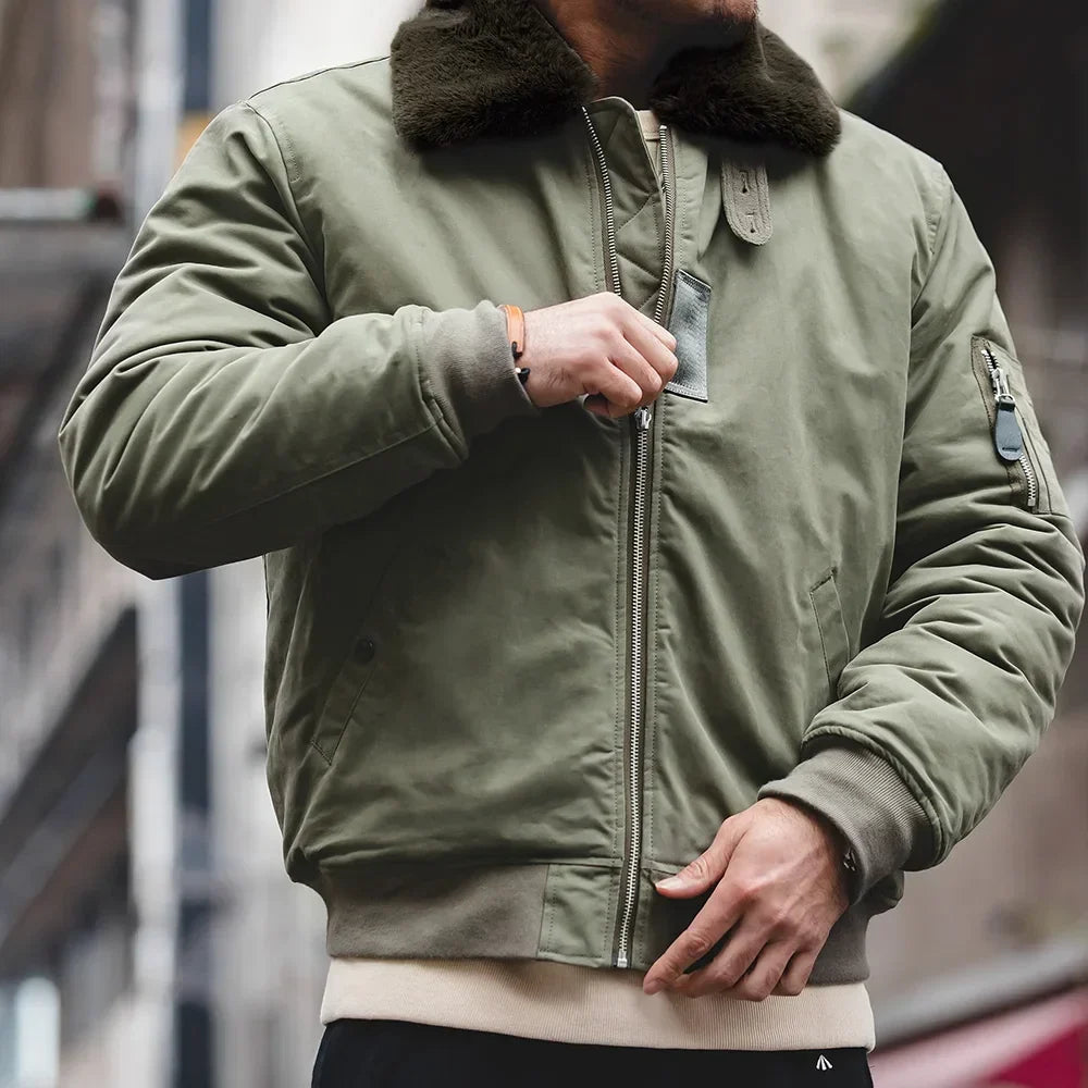 Person wearing a green jacket with a fur-lined hood in an urban setting