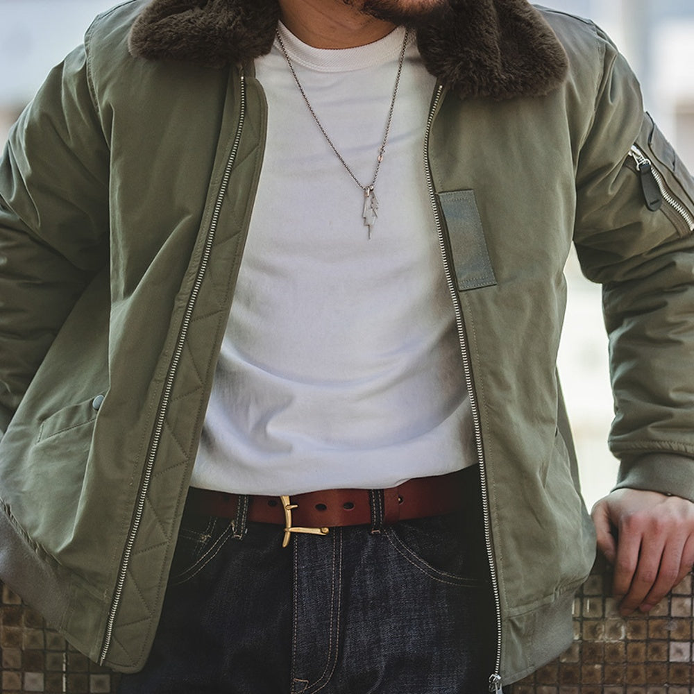 Person wearing a green jacket with fur collar, white shirt, and dark jeans.