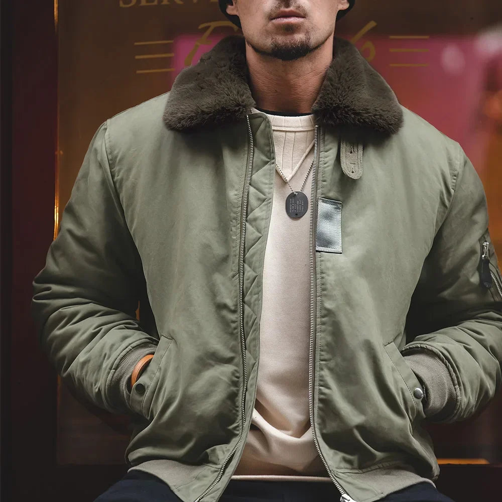 Person wearing a green jacket with a fur collar against a blurred background