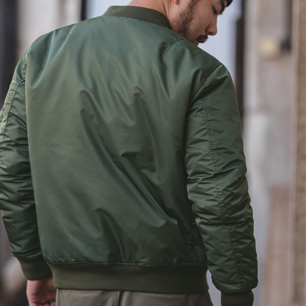 Person wearing a green bomber jacket with a blurred background
