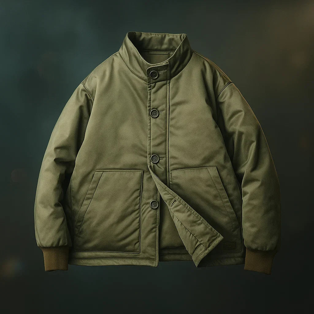 An olive green military-style jacket with a high stand-up collar, three-quarter button closure, and front flap pockets, shown against a dark, moody background.