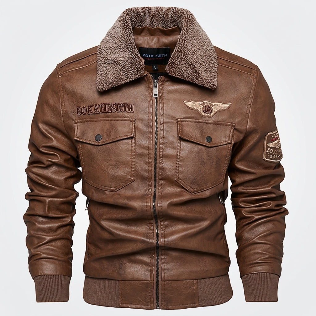 A brown faux-leather bomber jacket with a brown sherpa fleece collar, featuring zippered chest pockets, embroidered patches on the chest and sleeve, and ribbed cuffs and hem.
