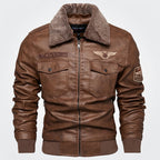 A brown faux-leather bomber jacket with a brown sherpa fleece collar, featuring zippered chest pockets, embroidered patches on the chest and sleeve, and ribbed cuffs and hem.