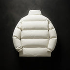 A cream-colored puffer jacket shown from the back, featuring horizontal quilting, a high collar, and elastic cuffs, set against a dark textured background.