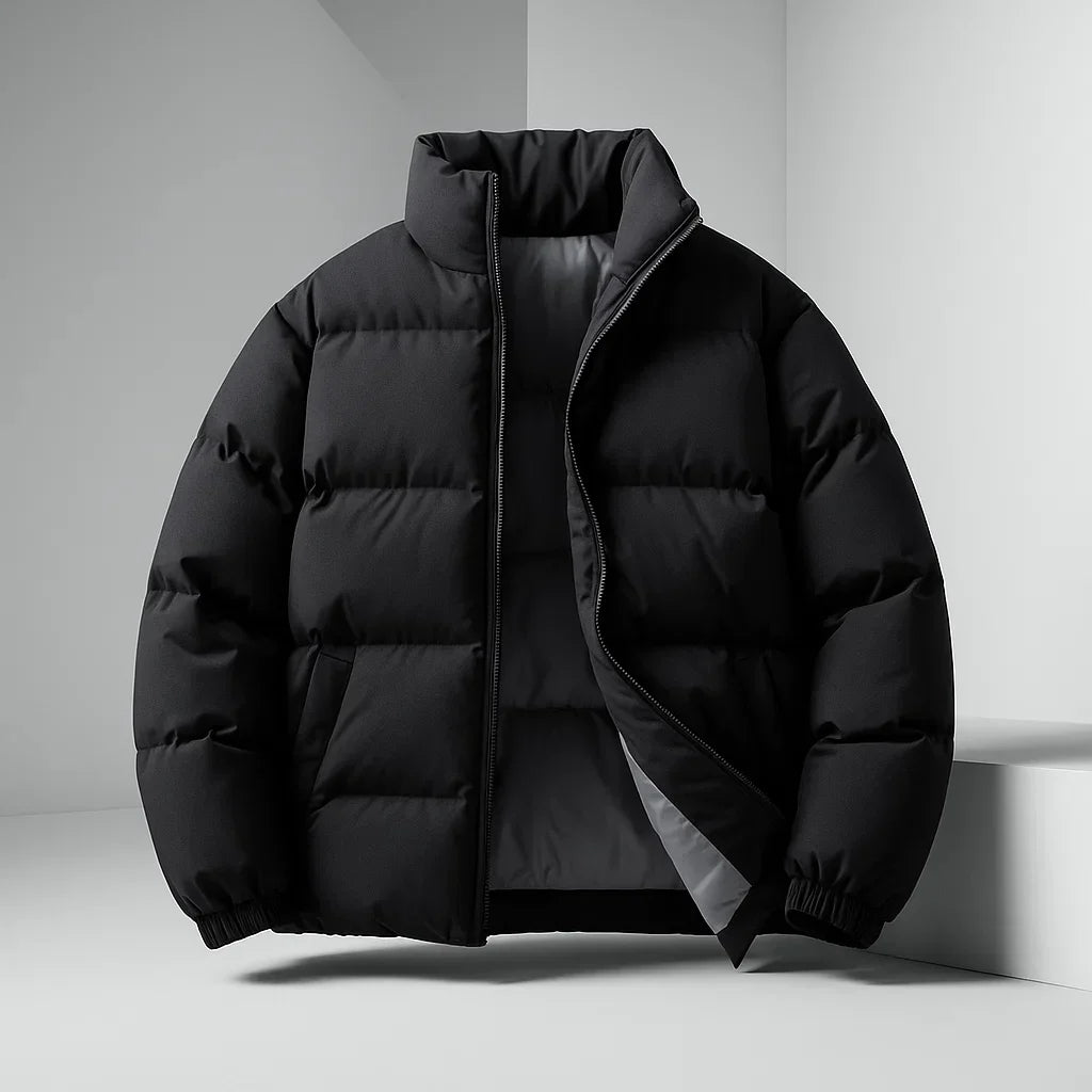 A black puffer jacket with a high stand-up collar and front zipper, displayed on a white geometric platform against a light gray studio background.