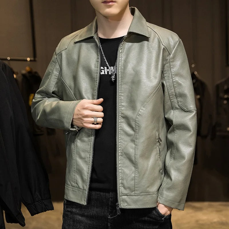 Person wearing a green jacket over a black shirt with visible branding, standing against a blurred indoor background.