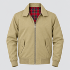 A beige zip-up jacket with a red and black plaid lining, featuring a collar, front zipper, buttoned flap pockets, and a red hanging zipper pull with white text.