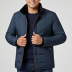 Man wearing a navy quilted jacket on a light gray background