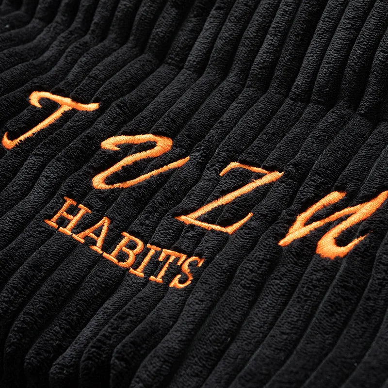 Black fabric with orange embroidered text on a textured background
