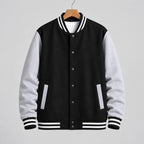 Black and gray varsity jacket on a hanger against a tiled wall.