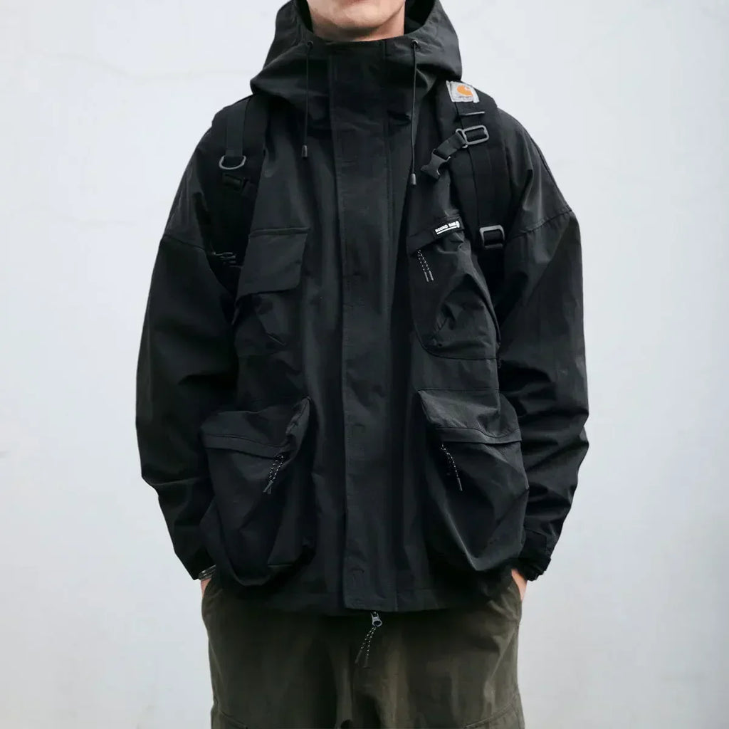 Person wearing a black jacket with a backpack on a plain background