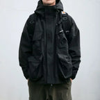 Person wearing a black jacket with a backpack on a plain background
