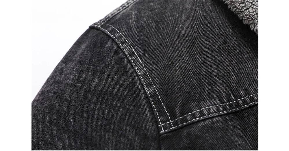 Close-up of a black denim jacket with stitching detail on a white background
