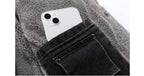 White smartphone in a pocket of black jeans with a gray textured background