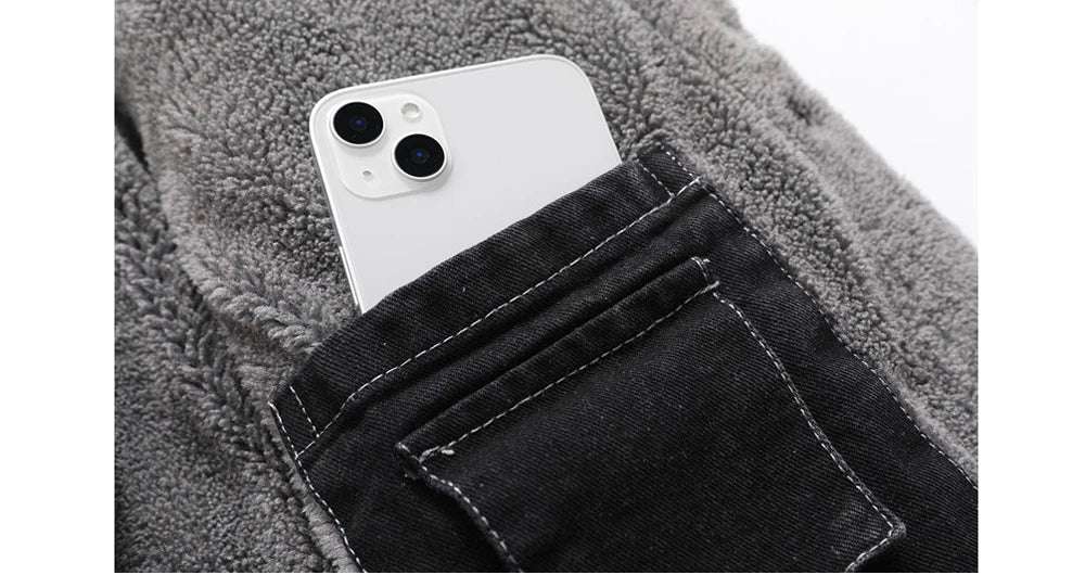 White smartphone in a pocket of black jeans with a gray textured background