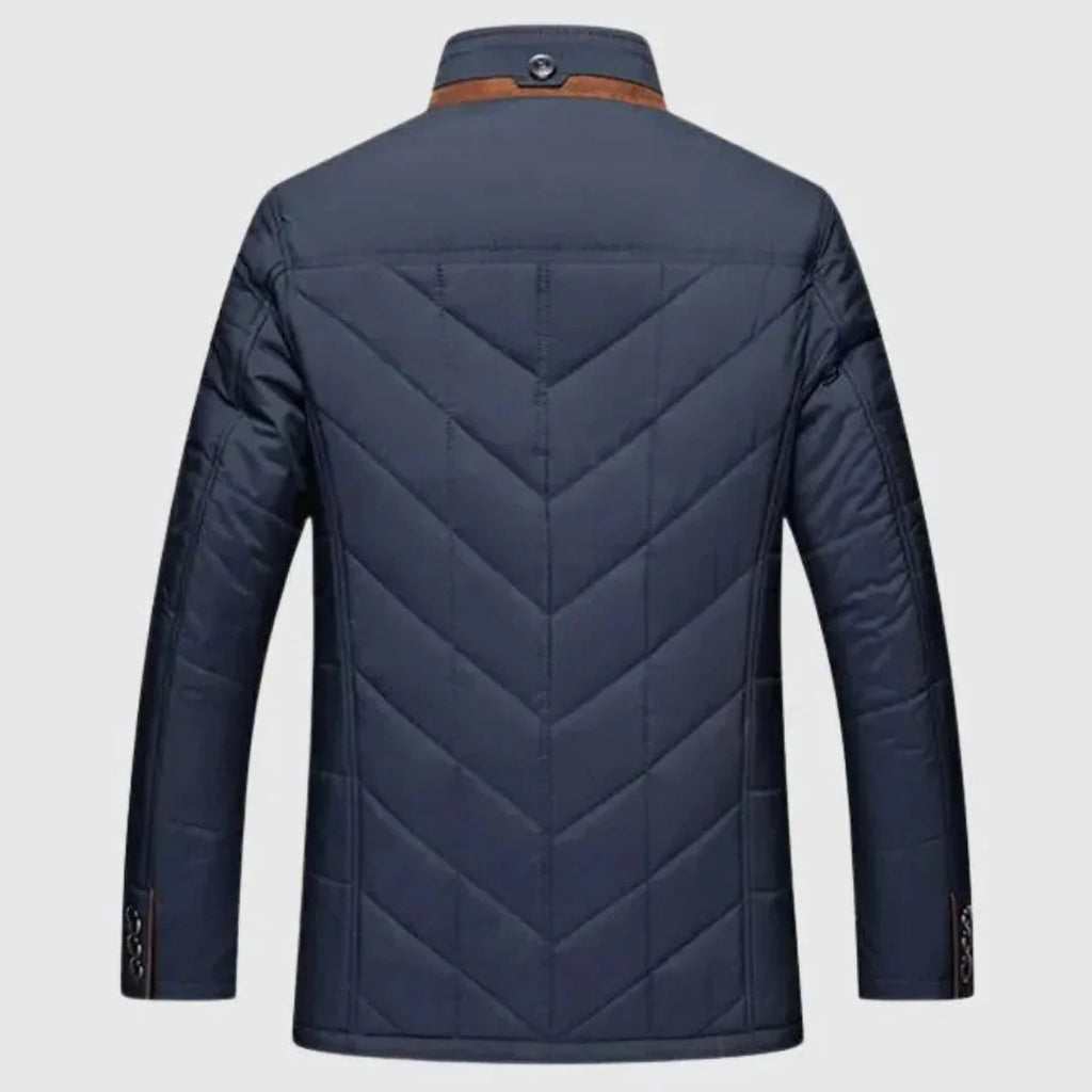 A men's quilted jacket shown from the back, featuring a deep V-pattern on the back panel and sleeves, a brown collar accent, and button details on the cuffs, set against a light gray background.
