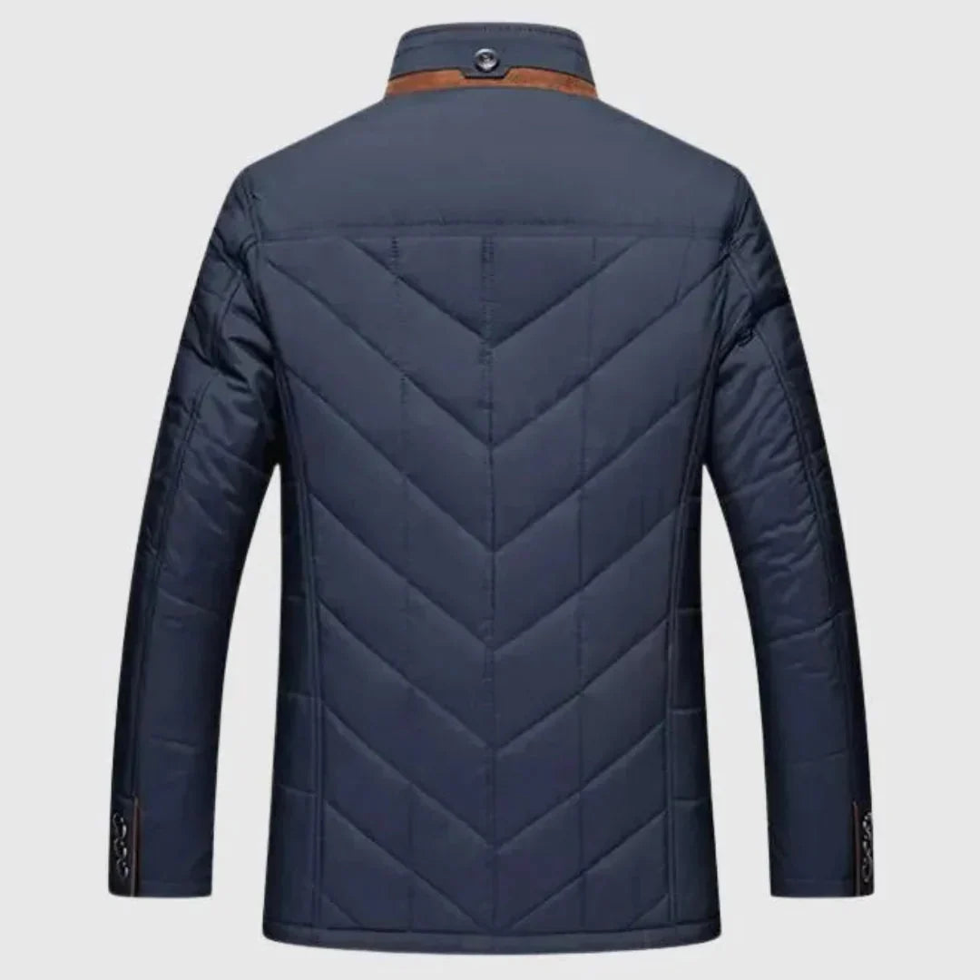 A men's quilted jacket shown from the back, featuring a deep V-pattern on the back panel and sleeves, a brown collar accent, and button details on the cuffs, set against a light gray background.